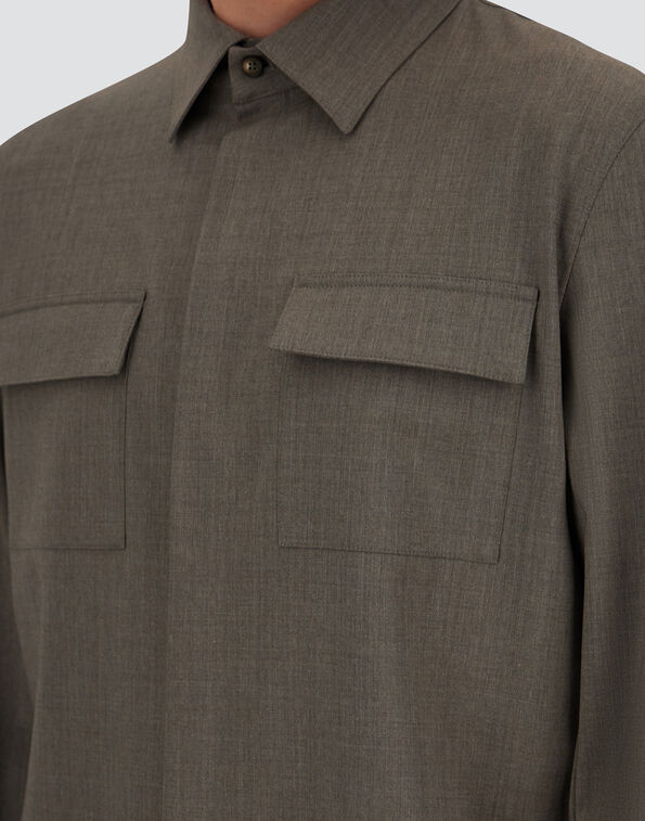 Close-up of a brown utility shirt with two flap pockets on the chest and a pointed collar.
