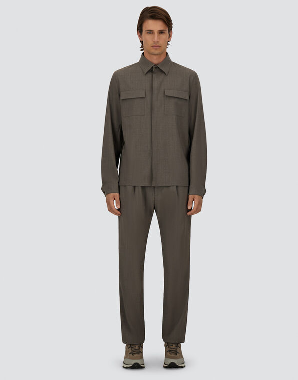 Full-body image of a man wearing a gray utility shirt with two chest pockets and matching straight-leg pants, beige sneakers