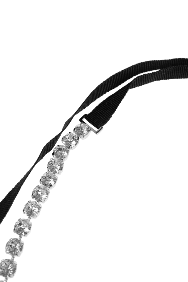 Close-up of a diamond tennis necklace laid along a black ribbon on a white background.