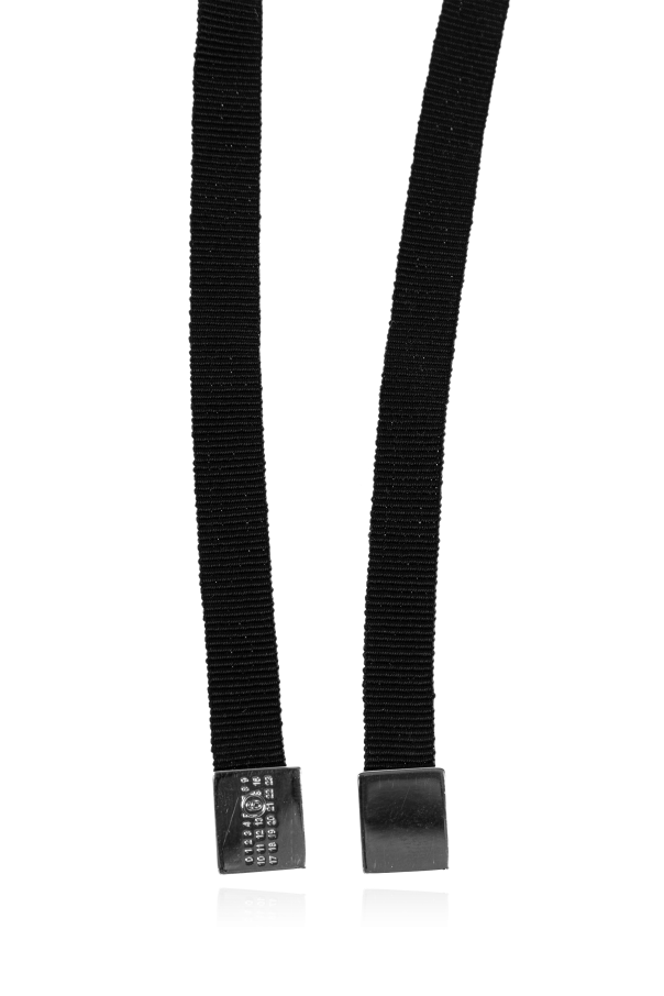 Close-up of two black elastic suspenders with silver metal clips resting on a reflective surface.