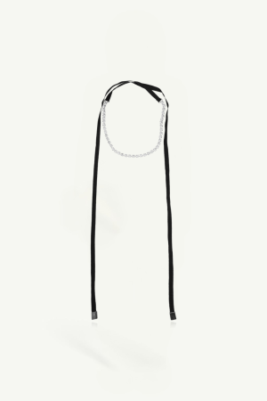 Choker necklace with a thin silver chain and long black ribbon ties against a pale background.
