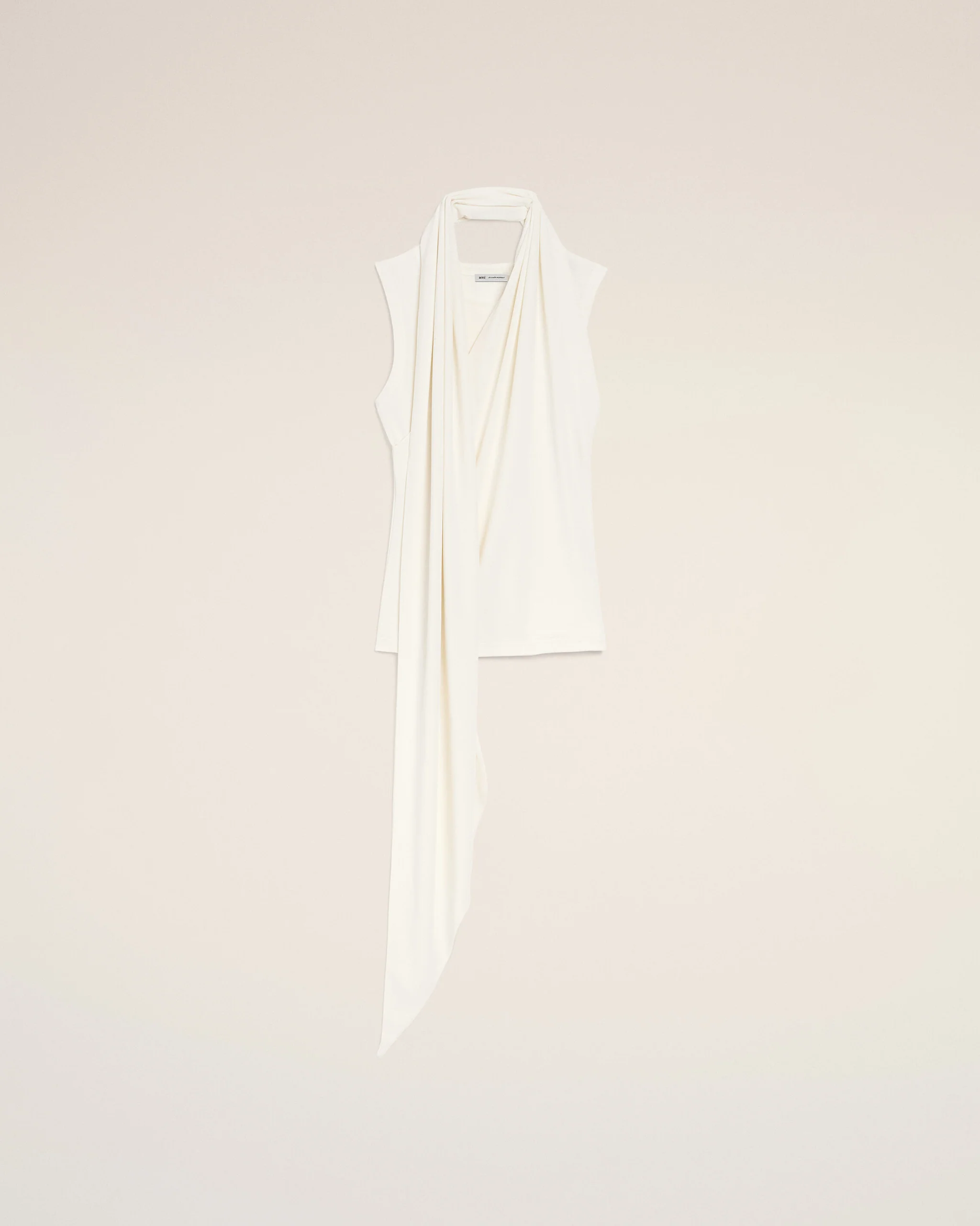 White scarf draped over a hanger against a pale beige background in a minimalist display