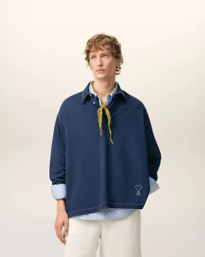 Person facing slightly left, wearing a navy shirt with a yellow scarf, against a pale background.