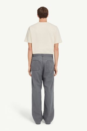 Back view of a person wearing an off-white short-sleeved T-shirt and gray wide-leg pants with patch pockets.