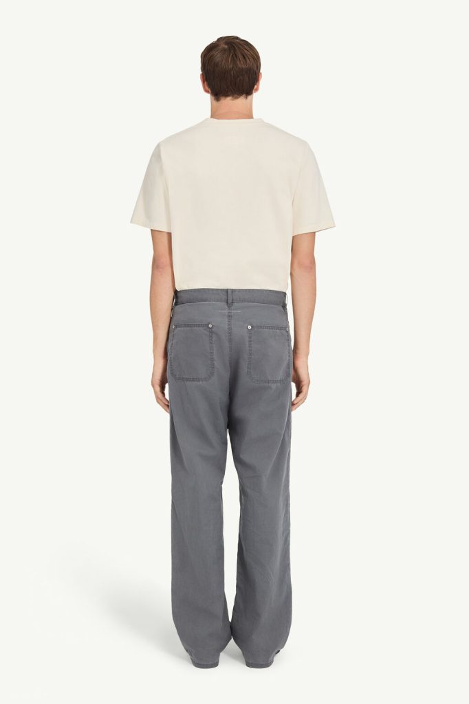 Back view of a person wearing an off-white short-sleeved T-shirt and gray wide-leg pants with patch pockets.