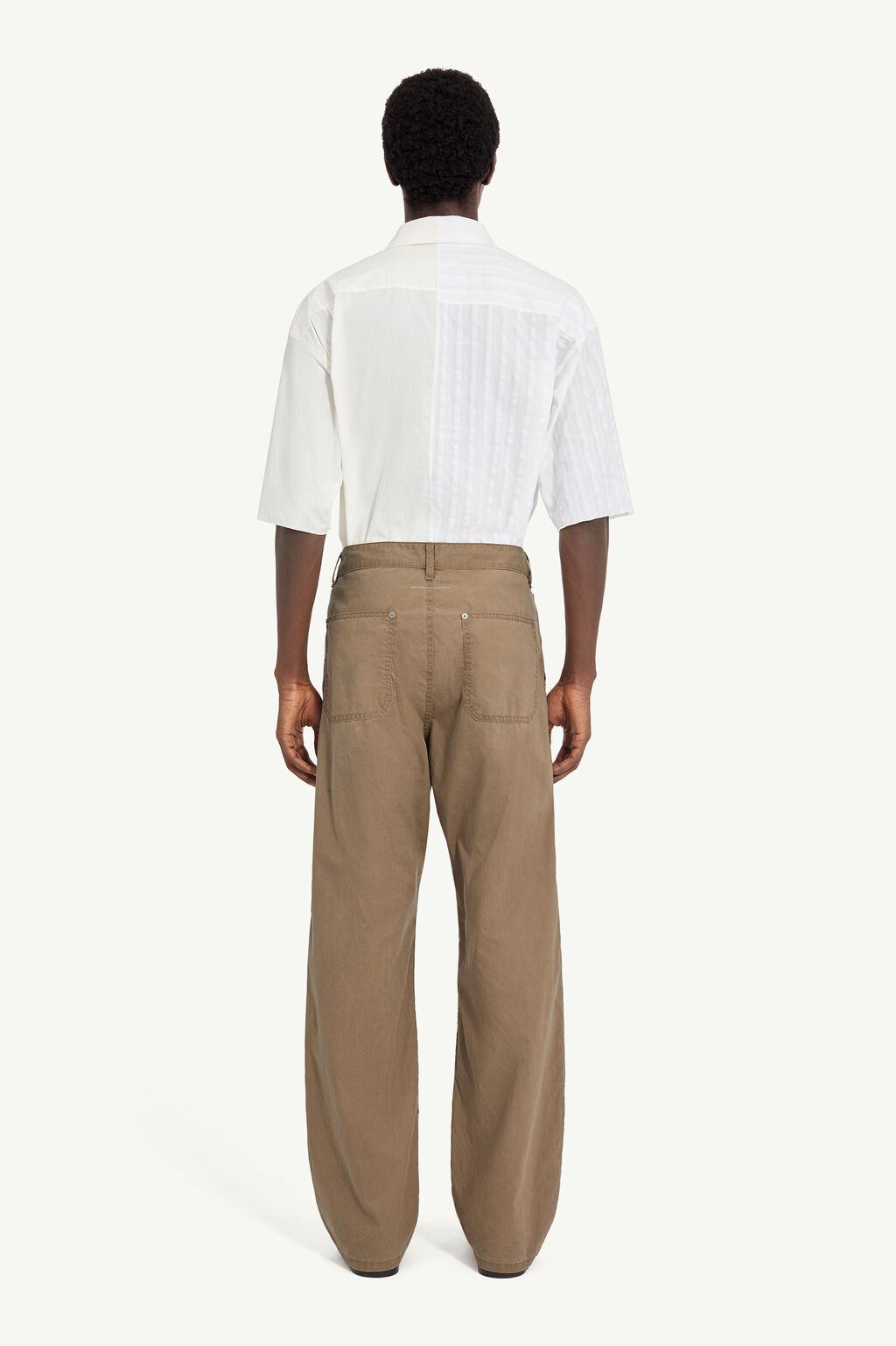 Back view of a person wearing a white short-sleeve shirt and tan wide-leg pants.