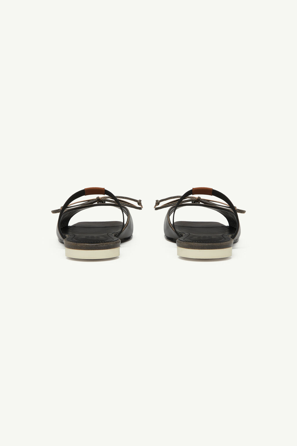 Pair of black sandals seen from behind with ankle straps and light soles on a pale background.