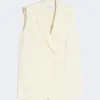 Cream sleeveless blazer with a notched lapel, open front, and front pockets on a light background.