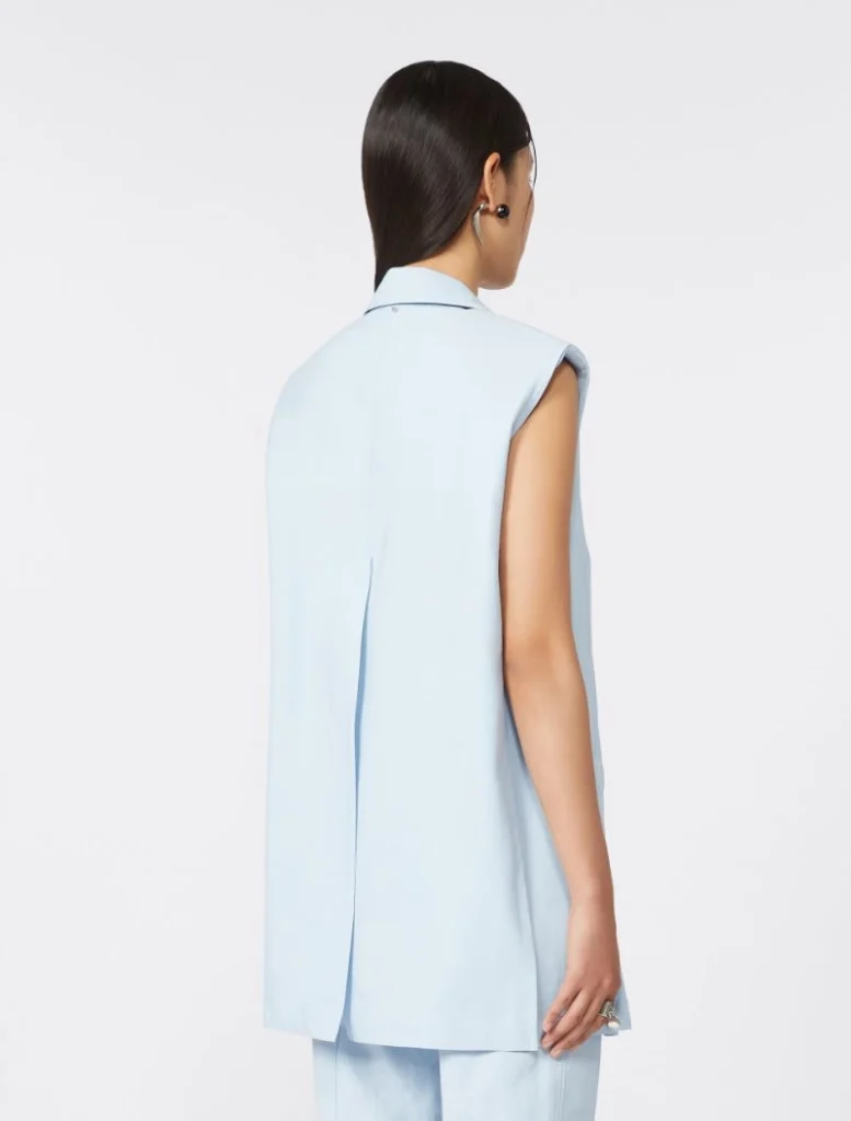 Back view of a woman wearing a light blue sleeveless vest with a collar, paired with matching pants.