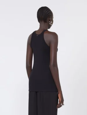 Back view of a person wearing a black ribbed tank top and black wide-leg pants, facing away from the camera with braided hair and silver jewelry. Back view of a model in a black sleeveless top and black trousers, accessorized with silver rings and earrings.