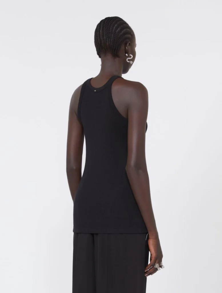 Back view of a person wearing a black ribbed tank top and black wide-leg pants, facing away from the camera with braided hair and silver jewelry. Back view of a model in a black sleeveless top and black trousers, accessorized with silver rings and earrings.