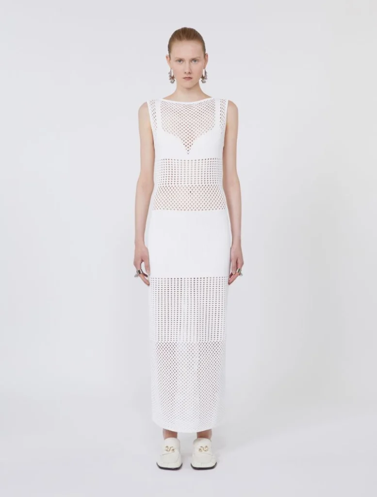 Full-length white mesh dress with perforated panels worn by a model against a plain backdrop.