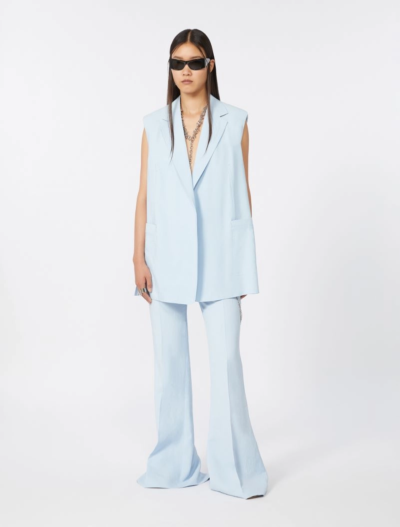 Model wearing a light blue sleeveless blazer and matching wide-leg pants with sunglasses.",