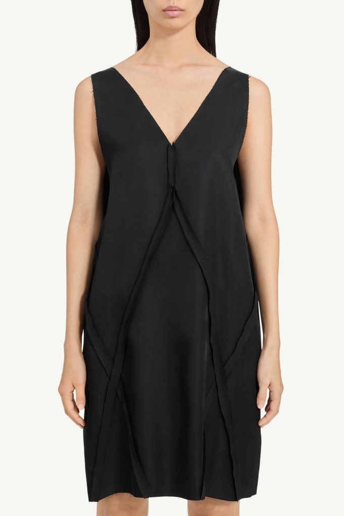 Black sleeveless dress with a plunging V-neck and draped front panels, knee-length, worn by a model.