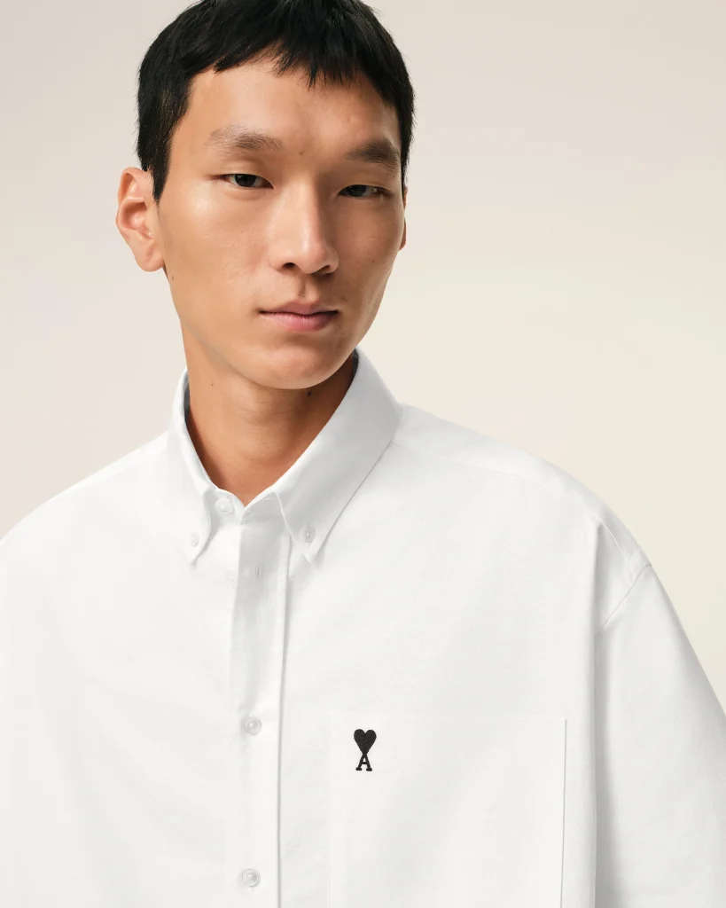 Portrait of a man in a white shirt with an Ace of Hearts card visible in his chest pocket, looking to the left.