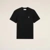 Black short-sleeve T-shirt with a small white heart-and-letter logo on the chest against a beige backdrop.