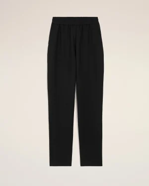 Black pants with an elastic waistband, full-length, shown against a light beige background (informative product image).