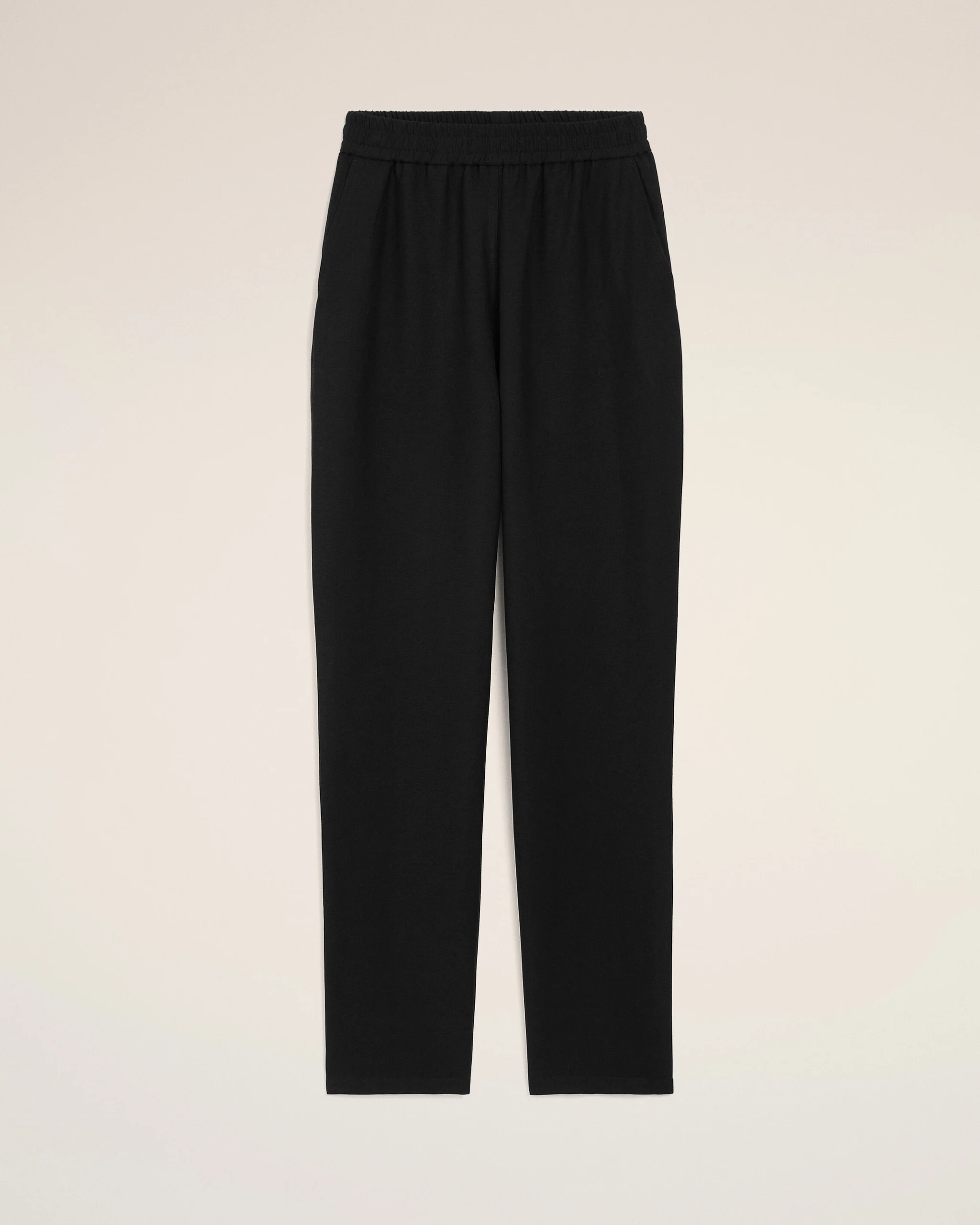 Black pants with an elastic waistband, full-length, shown against a light beige background (informative product image).