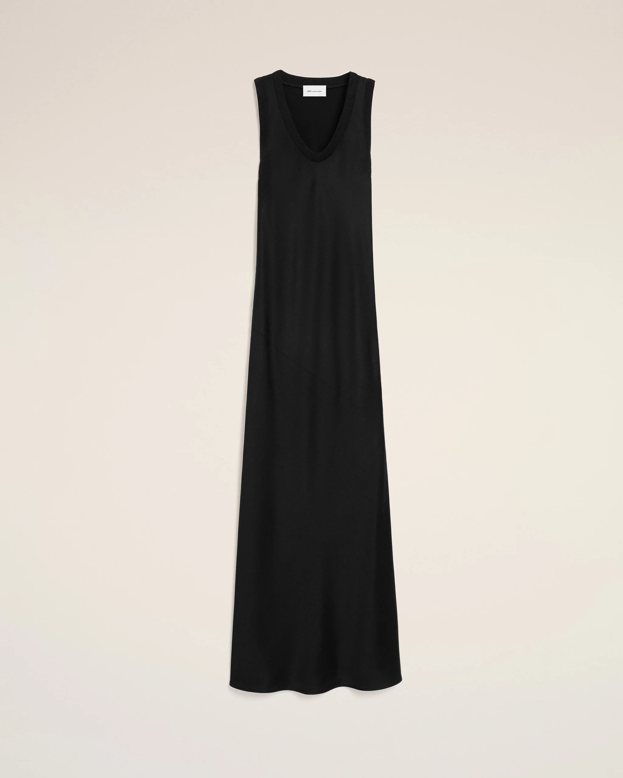 Long black sleeveless dress with a deep V-neck displayed against a pale beige background.