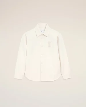 White button-down shirt with a small bear embroidery on the left chest, displayed against a pale beige background.