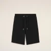 Front view of black shorts with a drawstring waist and metal-tipped ends, against a light beige background.