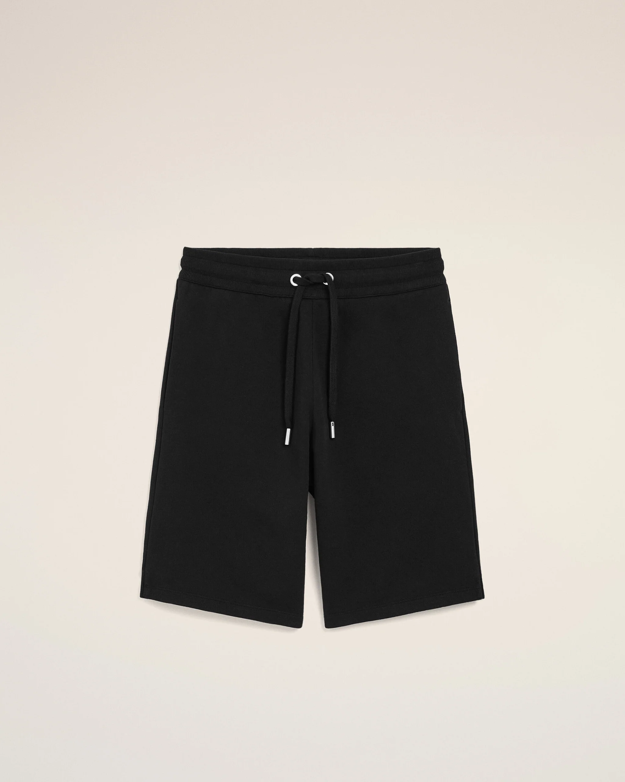 Front view of black shorts with a drawstring waist and metal-tipped ends, against a light beige background.