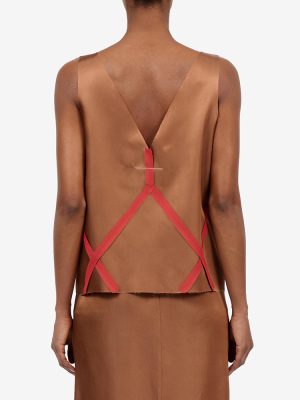 Back view of a brown satin sleeveless top with pink crisscross straps forming a geometric pattern on the back.