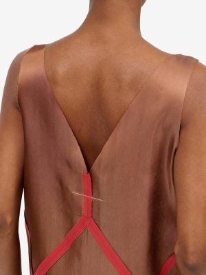Back view of a brown satin dress with red crisscross straps forming an X at the lower back.