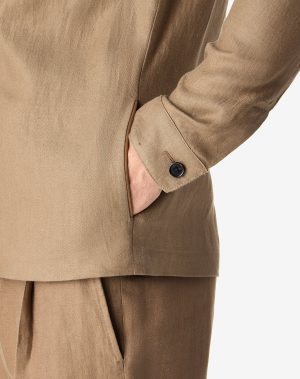 Close-up of a tan blazer sleeve with a pocket and cuff visible on the right side.