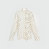 Cream polka-dot blouse with a ruffled front and button placket along the left side.