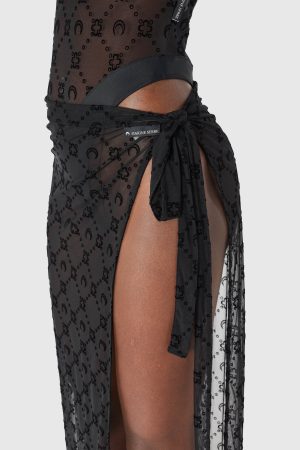 Close-up of sheer black fabric with a repeating pattern and a tied waist, showing a Marine Serre label.
