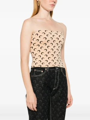 Beige strapless top with a black crescent moon pattern worn with dark jeans.
