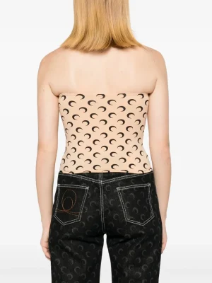 Back view of a person wearing a strapless beige top with a black crescent pattern and dark jeans with curved stitch pockets.