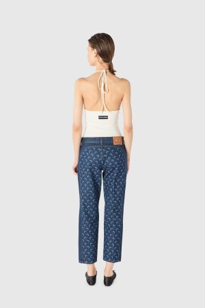 Back view of a woman wearing a white halter top and blue patterned jeans, hair in a low ponytail.