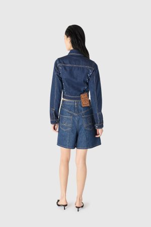 Back view of a person wearing a denim jacket and matching high-waisted shorts, facing away.