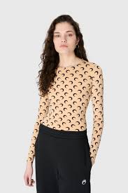 Model wearing a beige long-sleeve top with a repeating crescent pattern, paired with a black skirt.
