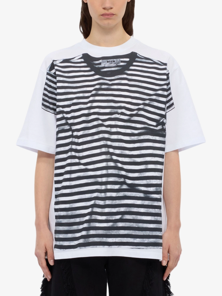 Woman wearing a white oversized T-shirt with black horizontal stripes across the front, standing facing the camera