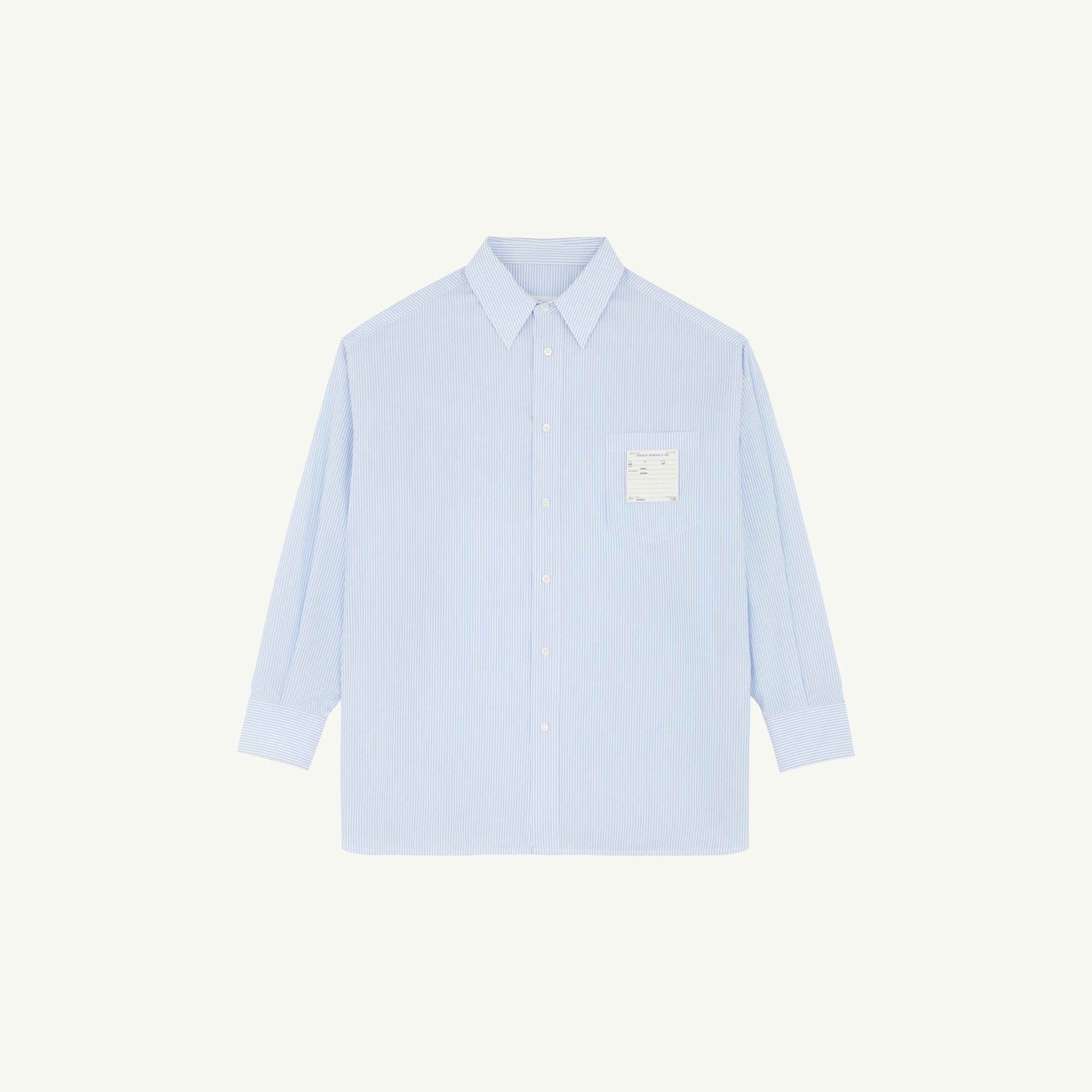Front view of a light blue striped dress shirt with a pointed collar and visible buttons against a pale background.