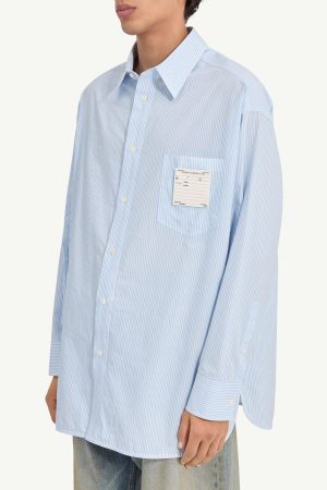 Oversized light blue striped button-down shirt with a chest pocket and a label on the pocket.