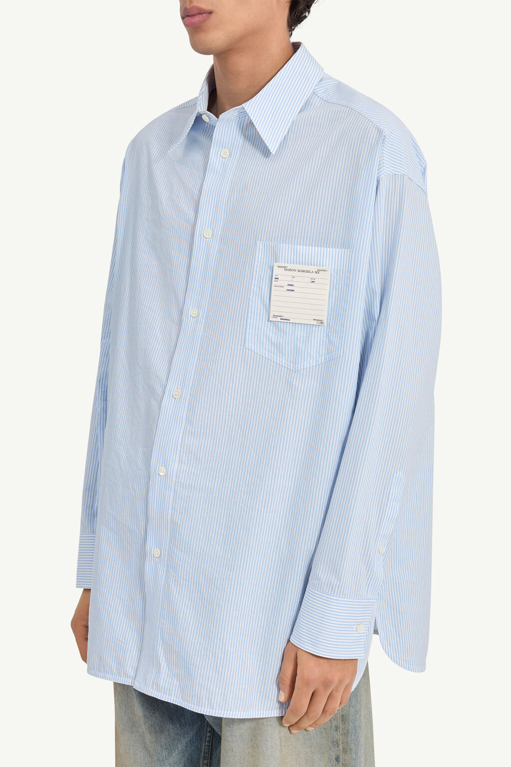 Oversized light blue striped button-down shirt with a chest pocket and a label on the pocket.