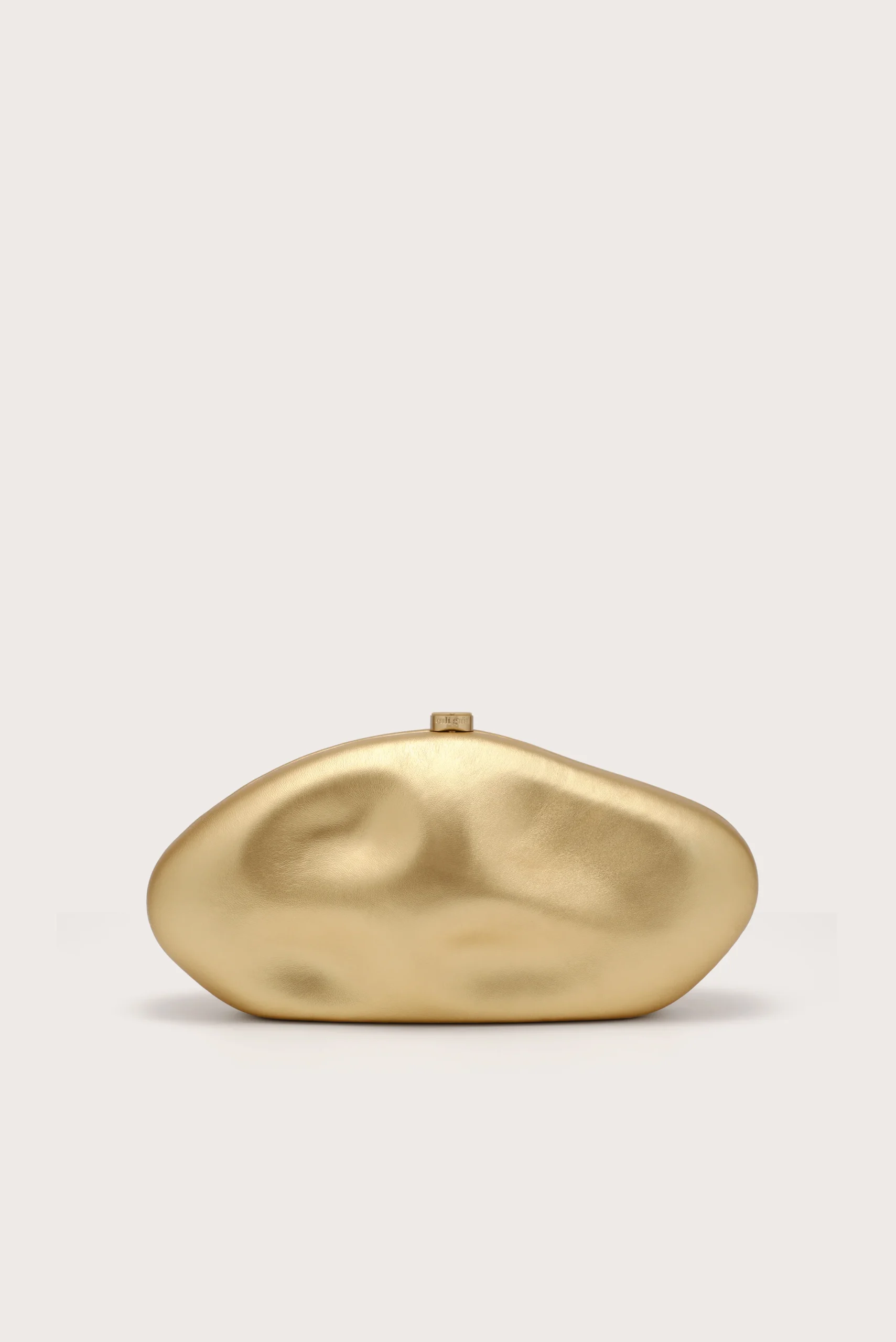 Gold-toned, abstract organic sculpture on a light beige background with soft shadows.