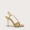 Gold strappy high-heeled sandal shown from a side angle with stiletto heel on a light background, partial view of the shoe close to bottom left
