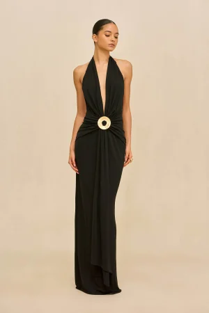 Full-length black halter gown on a woman, deep V neckline and a large gold circular belt.