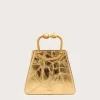 Gold-toned metallic handbag with a rounded hinge handle against a pale background, front view