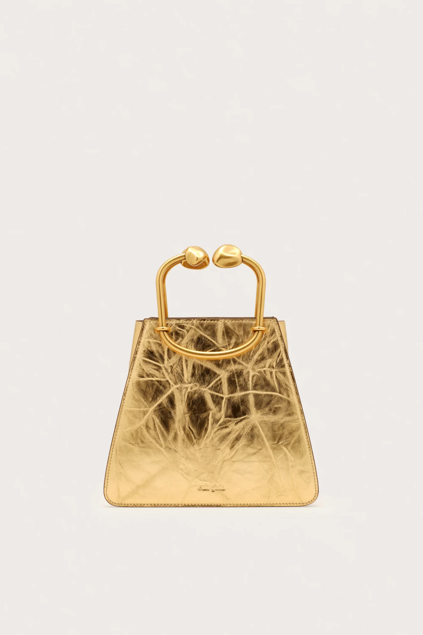 Gold-toned metallic handbag with a rounded hinge handle against a pale background, front view