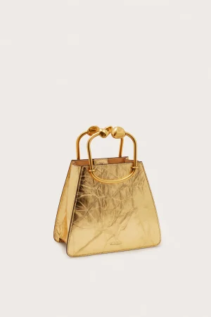 Gold metallic handbag with large rounded gold handles against a light background.