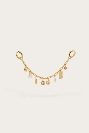 Gold-toned charm necklace with multiple dangling charms, suspended against a pale background.
