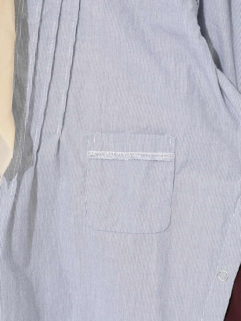 Close-up of a light blue and white striped shirt with a chest pocket and visible stitching.
