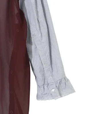 Close-up of two-toned shirt sleeves: burgundy fabric beside a light blue pinstriped sleeve with snap buttons and a ruffled cuff.