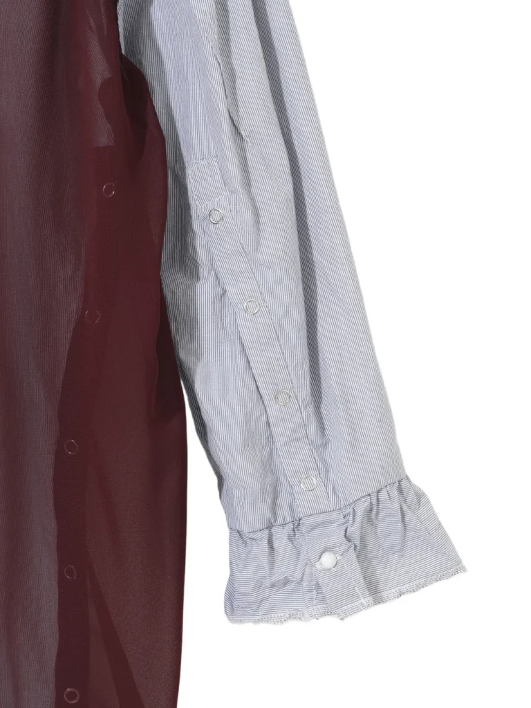 Close-up of two-toned shirt sleeves: burgundy fabric beside a light blue pinstriped sleeve with snap buttons and a ruffled cuff.
